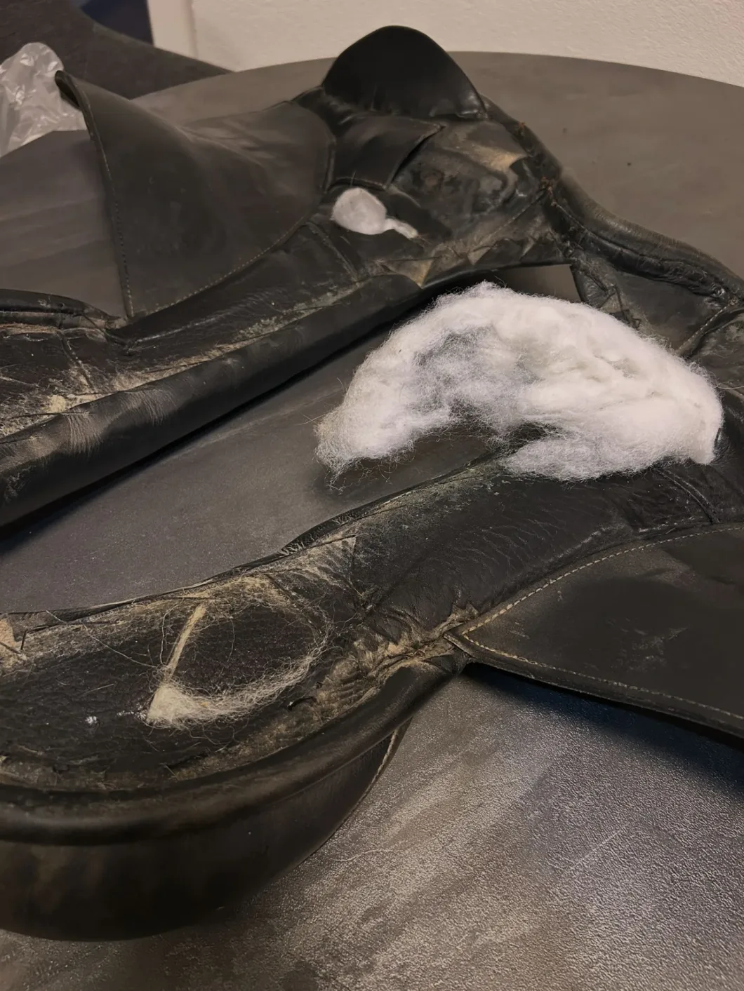 Defekte Satteldecke mit sichtbarem Füllmaterial, zeigt starke Abnutzung und Beschädigung.